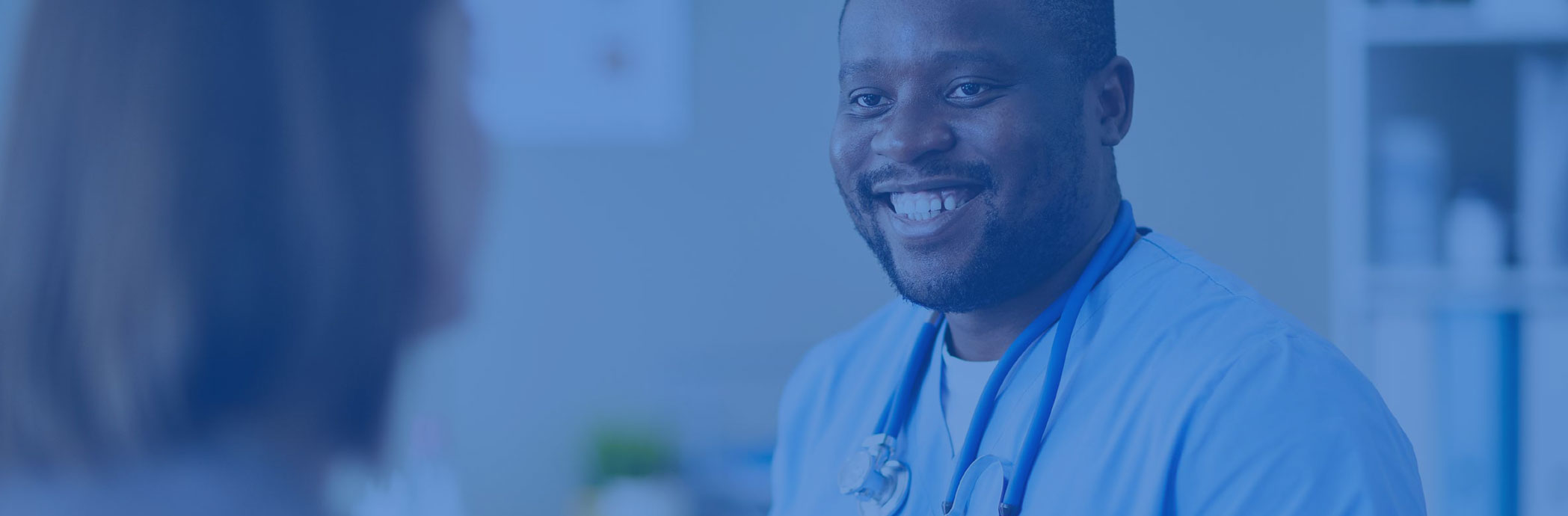 Smiling doctor wearing blue scrubs.